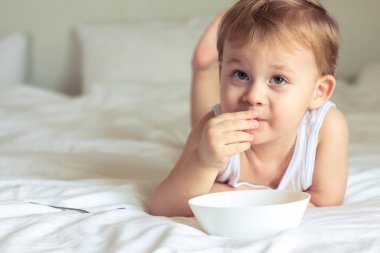 Yatakta kahvaltı küçük şirin çocuk. Yatakta oynayan çocuk. Yatakta kahvaltı.