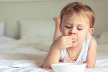 Yatakta kahvaltı küçük şirin çocuk. Yatakta oynayan çocuk. Yatakta kahvaltı.