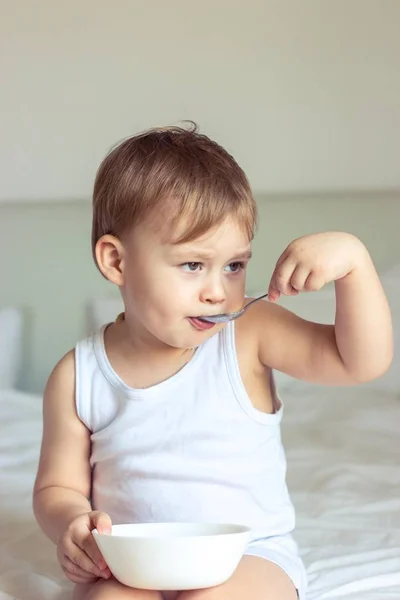 Schattig jongetje ontbijten in bed. Jongen spelen in bed. Ontbijt op bed. — Stockfoto