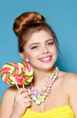 Mavi bir arka plan üzerinde şeker ile güzel bir genç kadın portresi. Sarışın renkli şeker ile. Tatlı. Parlak kadınla