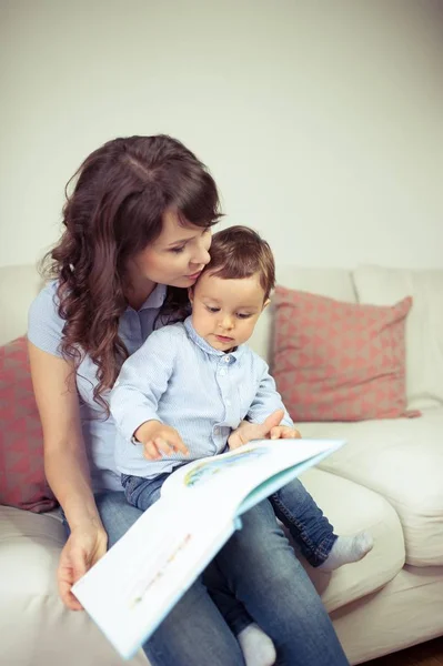 A jovem mãe lê um livro com um filho jovem. Bonito menino e sua mãe . — Fotografia de Stock