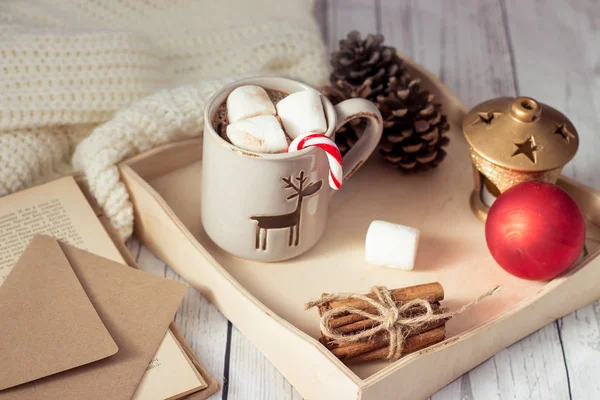 Weihnachtsstimmung. Gemütliches Weihnachtsfrühstück. Plaid, ein Tablett, ein Becher heißen Kakao, Marshmallows. das Buch und die Weihnachtskarte. — Stockfoto