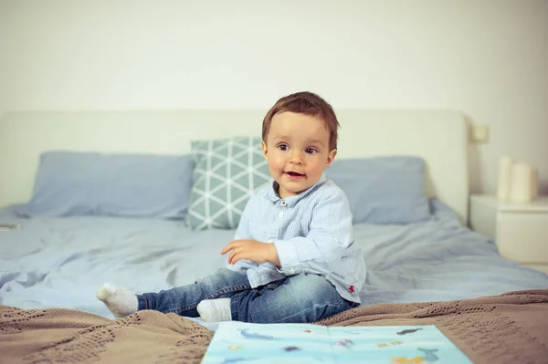 Jongetje speelt op het bed. Een gelukkig klein kind. — Stockfoto