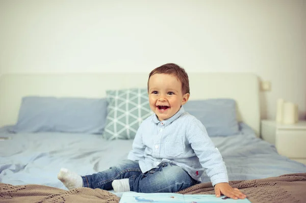 Il bambino gioca sul letto. Un bambino felice . — Foto Stock