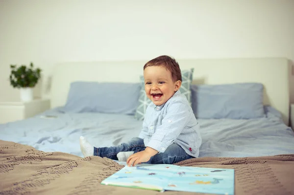 Il bambino gioca sul letto. Un bambino felice . — Foto Stock