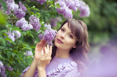 Genç güzel kadın bahar bahçe yürür. Bir kız leylak duruyor. Leylak. Çiçekler.