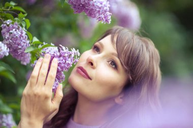 Genç güzel kadın bahar bahçe yürür. Bir kız leylak duruyor. Leylak. Çiçekler.