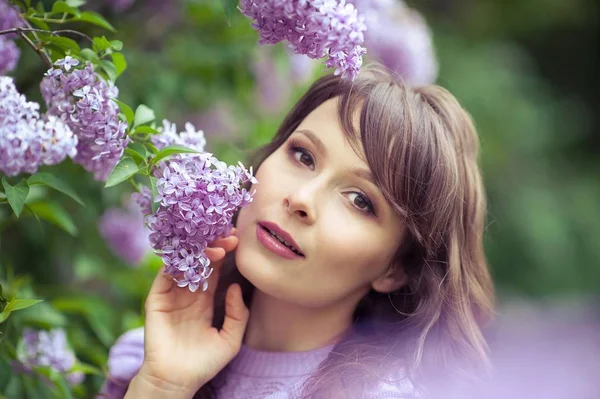 Genç güzel kadın bahar bahçe yürür. Bir kız leylak duruyor. Leylak. Çiçekler. — Stok fotoğraf