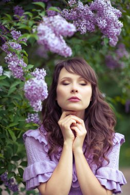 Genç güzel kadın bahar bahçe yürür. Bir kız leylak duruyor. Leylak. Çiçekler.