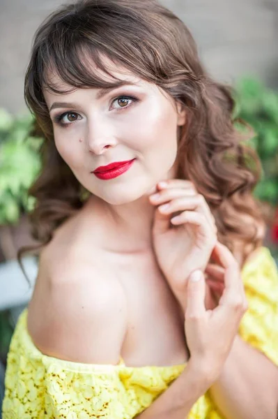 Portret van een mooie jonge vrouw in een gele jurk met rode lippenstift. Lente portret van een meisje. — Stockfoto
