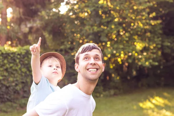 父と息子は、夕日で歩きます。幸せなお父さんと太陽の下で息子の若い. — ストック写真