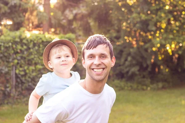 父と息子は、夕日で歩きます。幸せなお父さんと太陽の下で息子の若い. — ストック写真