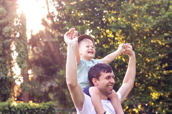 Πατέρας και γιος με τα πόδια στο ηλιοβασίλεμα. Χαρούμενος ο μπαμπάς και ο μικρός γιος στον ήλιο. — Φωτογραφία Αρχείου