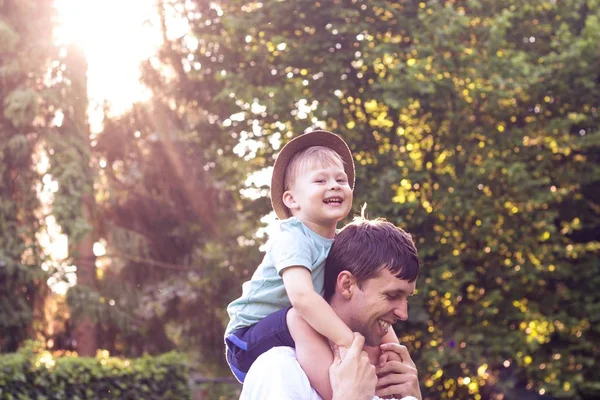 父と息子は、夕日で歩きます。幸せなお父さんと太陽の下で息子の若い. — ストック写真