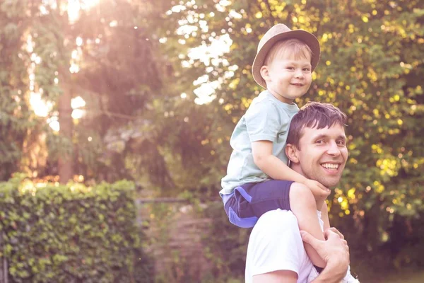 父と息子は、夕日で歩きます。幸せなお父さんと太陽の下で息子の若い. — ストック写真