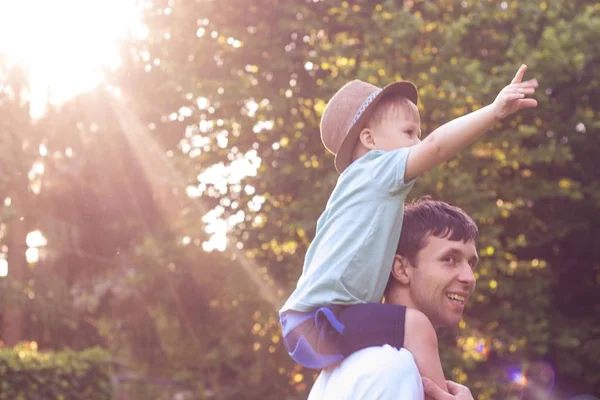 父と息子は、夕日で歩きます。幸せなお父さんと太陽の下で息子の若い. — ストック写真