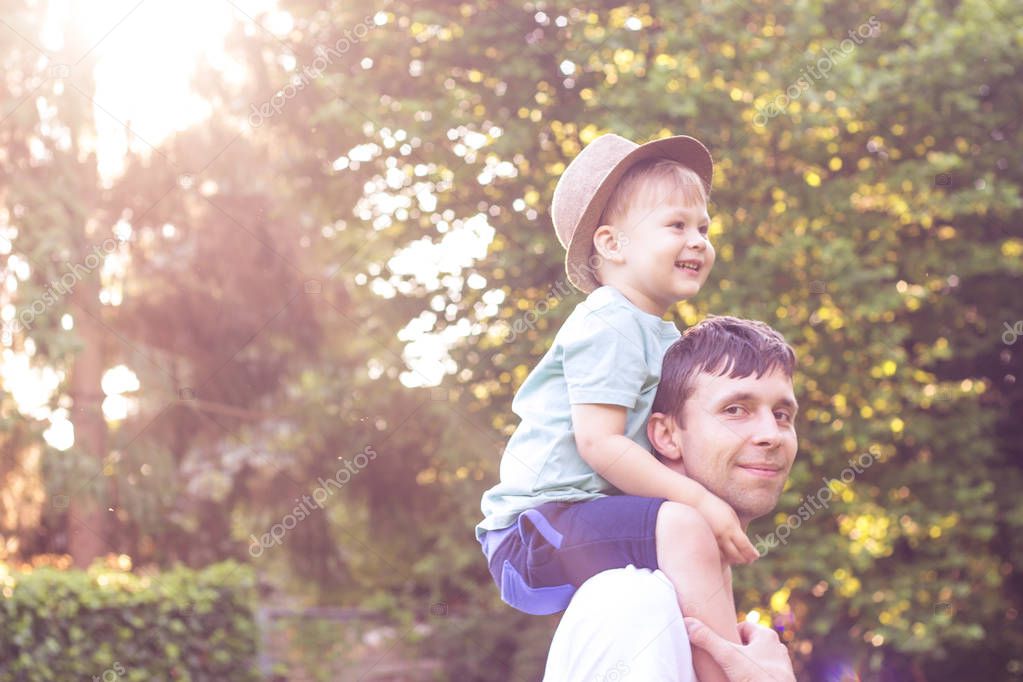 Father and son walk at sunset. Happy dad and young son in the Sun.