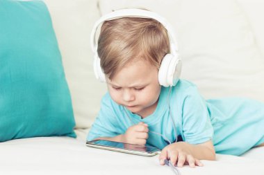 3 yıl yaşlı erkek çocuk koltukta oturur ve müzik dinliyor. Telefonda çizgi film izlerken küçük şirin çocuk. Küçük çocuk.