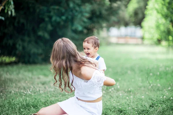 Anne ve genç oğlu çimenlerin üzerinde oynadı. Mutlu aile parkta yürüyor. Karpuz yeme anne ve genç oğlu. Piknik. Yaz. — Stok fotoğraf