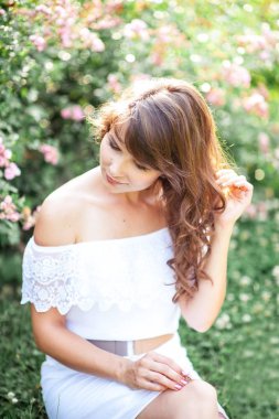 Genç güzel kadın çiçekli parkta yürüyor. Genç bir kadın portresi. Mutlu kız. Yaz.