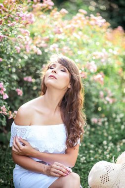 Genç güzel kadın çiçekli parkta yürüyor. Genç bir kadın portresi. Mutlu kız. Yaz.