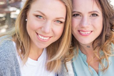 İki arkadaş şehrin içinden yürümek ve kapuçino içmek. İki genç kadın Cafe oturuyor. İletişim sıcak bahar. Yaz.