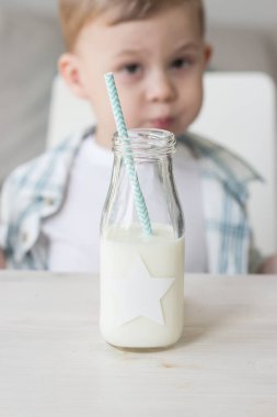 Sevimli küçük bir çocuk şeker yemek ve süt içme. Sağlık. Mutlu bir çocuk. Kahvaltı. Küçük bir oğlan masada oturuyor.