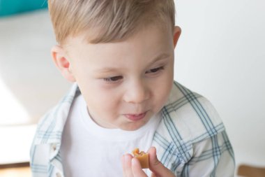 Sevimli küçük bir çocuk şeker yemek ve süt içme. Sağlık. Mutlu bir çocuk. Kahvaltı. Küçük bir oğlan masada oturuyor.