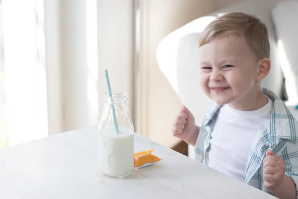 かわいい男の子はキャンディを食べる、牛乳を飲みます。健康。幸せな子。朝食。小さな男の子はテーブルに座っています。. — ストック写真