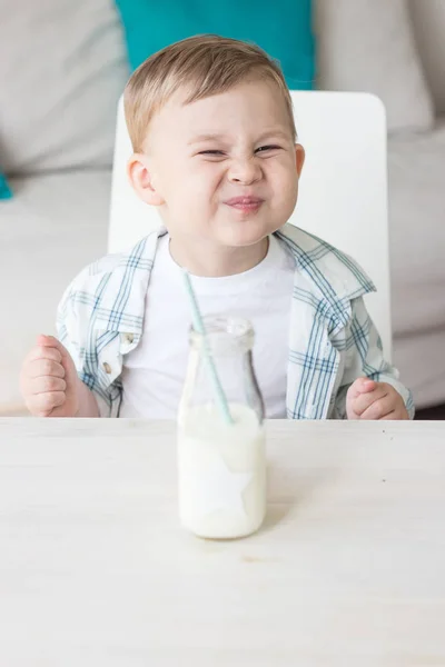 かわいい男の子はキャンディを食べる、牛乳を飲みます。健康。幸せな子。朝食。小さな男の子はテーブルに座っています。. — ストック写真