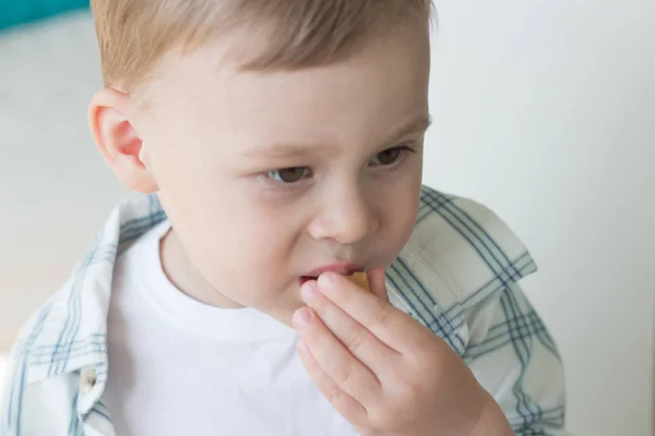 Een schattige kleine jongen is het eten van snoep en drinken van melk. Gezondheid. Gelukkig kind. Ontbijt. Een jongetje zit aan de tafel. — Stockfoto