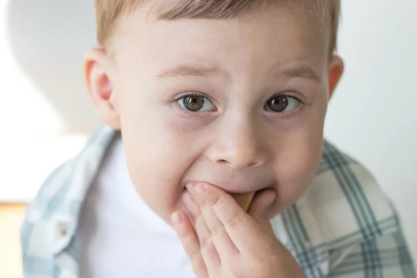 Een schattige kleine jongen is het eten van snoep en drinken van melk. Gezondheid. Gelukkig kind. Ontbijt. Een jongetje zit aan de tafel. — Stockfoto