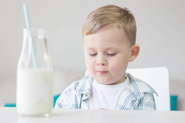 かわいい男の子はキャンディを食べる、牛乳を飲みます。健康。幸せな子。朝食。小さな男の子はテーブルに座っています。. — ストック写真