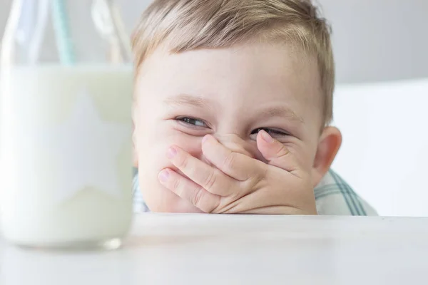 Een schattige kleine jongen is het eten van snoep en drinken van melk. Gezondheid. Gelukkig kind. Ontbijt. Een jongetje zit aan de tafel. — Stockfoto
