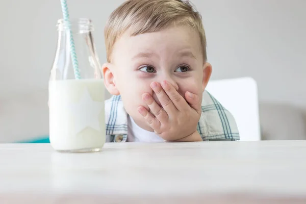 かわいい男の子はキャンディを食べる、牛乳を飲みます。健康。幸せな子。朝食。小さな男の子はテーブルに座っています。. — ストック写真