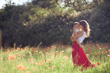 Güzel bir aile haşhaş alanına yürüyor. Küçük oğlu olan genç bir anne yürüyor. Yaz. Bahar.