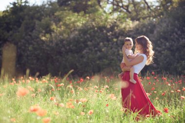 Güzel bir aile haşhaş alanına yürüyor. Küçük oğlu olan genç bir anne yürüyor. Yaz. Bahar.