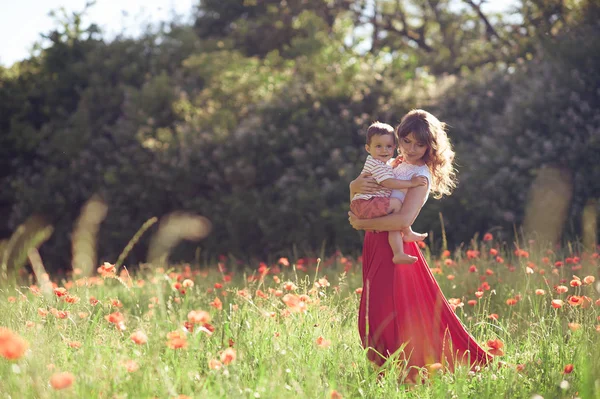 Güzel bir aile haşhaş alanına yürüyor. Küçük oğlu olan genç bir anne yürüyor. Yaz. Bahar.