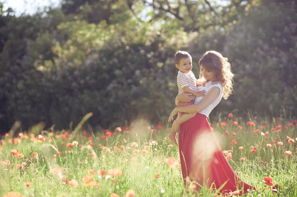 A beautiful family is walking in a poppy field. A young mother with a little son is walking. Summer. Spring. — Stock Photo, Image