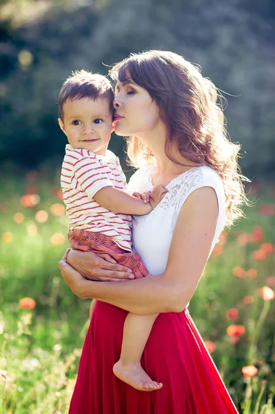 Güzel bir aile haşhaş alanına yürüyor. Küçük oğlu olan genç bir anne yürüyor. Yaz. Bahar.