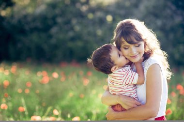 Güzel bir aile haşhaş alanına yürüyor. Küçük oğlu olan genç bir anne yürüyor. Yaz. Bahar.