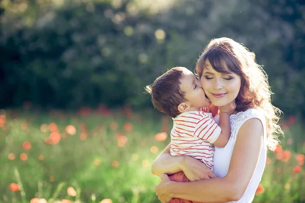 A beautiful family is walking in a poppy field. A young mother with a little son is walking. Summer. Spring. — Stock Photo, Image