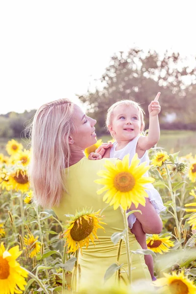 Family is walking along the summer flowering field. Happy mother and daughter in the sun. Summer. Sunflowers. — Stock Photo, Image