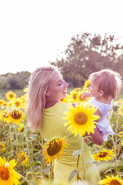 Family is walking along the summer flowering field. Happy mother and daughter in the sun. Summer. Sunflowers. — Stock Photo, Image