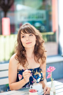 Güzel genç kadın bir kafede oturuyor. Bir kız kahve içer ve tatlı yiyor. Genç bir kadın şehirde yürüyüş.