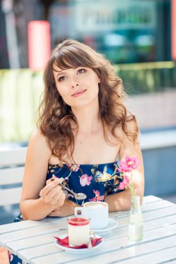 Güzel genç kadın bir kafede oturuyor. Bir kız kahve içer ve tatlı yiyor. Genç bir kadın şehirde yürüyüş.