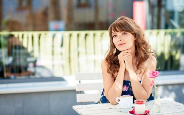 Güzel genç kadın bir kafede oturuyor. Bir kız kahve içer ve tatlı yiyor. Genç bir kadın şehirde yürüyüş.