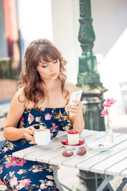 Güzel genç kadın bir kafede oturuyor. Bir kız kahve içer ve tatlı yiyor. Genç bir kadın şehirde yürüyüş.