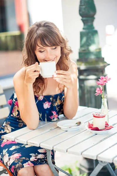 Güzel genç kadın bir kafede oturuyor. Bir kız kahve içer ve tatlı yiyor. Genç bir kadın şehirde yürüyüş.