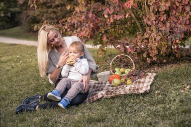 Güzel genç anne ve genç oğlu yürümek. Anne ve oğlunun sonbahar Park yürüyün. Sıcak sonbahar. Piknik.